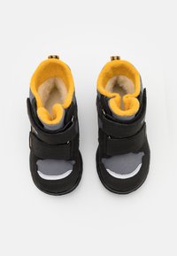 Stivaletti neri e grigi alla caviglia con due strisce in Velcro regolabili, foderati in pile giallo e suola in gomma texturizzata. Presentano pannelli in rete e dettagli bianchi.