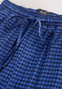 Shorts à carreaux bleus et noirs avec une taille élastique, un cordon de serrage et des plis. Confectionnés dans un tissu léger pour le confort et la respirabilité.