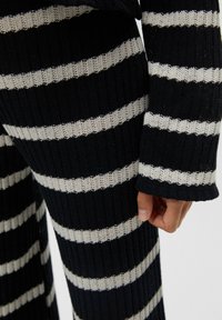 Ensemble de pull en maille avec des rayures horizontales bleu marine et crème, texture côtelée et manches longues. Le tissu semble doux et respirant.