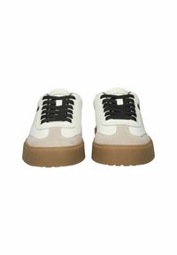 Pair of low-top white sneakers with brown soles, black laces, and suede accents, viewed from the front against a white background.
