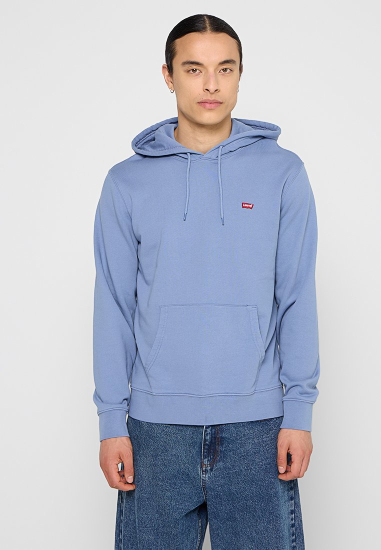 Sudadera azul claro hecha de un tejido suave, con un bolsillo canguro en la parte frontal, capucha ajustable con cordones, y un pequeño logo rojo en el pecho.