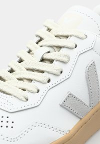 Witte leren sneaker met crèmekleurige veters, grijze suède accenten, geperforeerde details en een lichtbruine rubberen zool. Gevoerde kraag voor extra comfort.