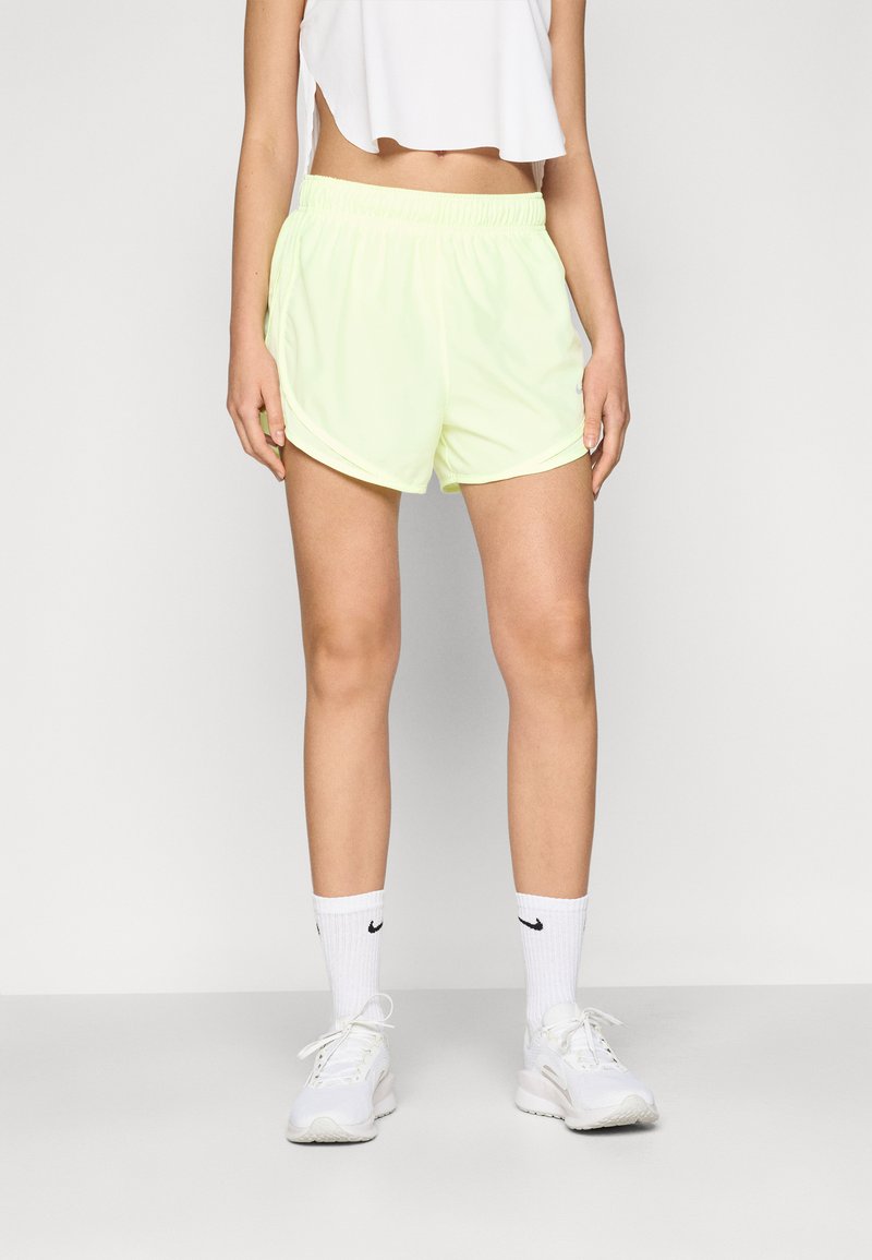 Shorts de sport jaune fluo avec une taille élastique, offrant une coupe ample et un ourlet légèrement arrondi. Portés avec des baskets blanches et des chaussettes.