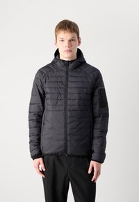 Casaco preto acolchoado com fecho éclair na frente e capuz, apresentando seções contrastantes acolchoadas e lisas. Inclui bolsos laterais e um bolso com fecho éclair na manga.