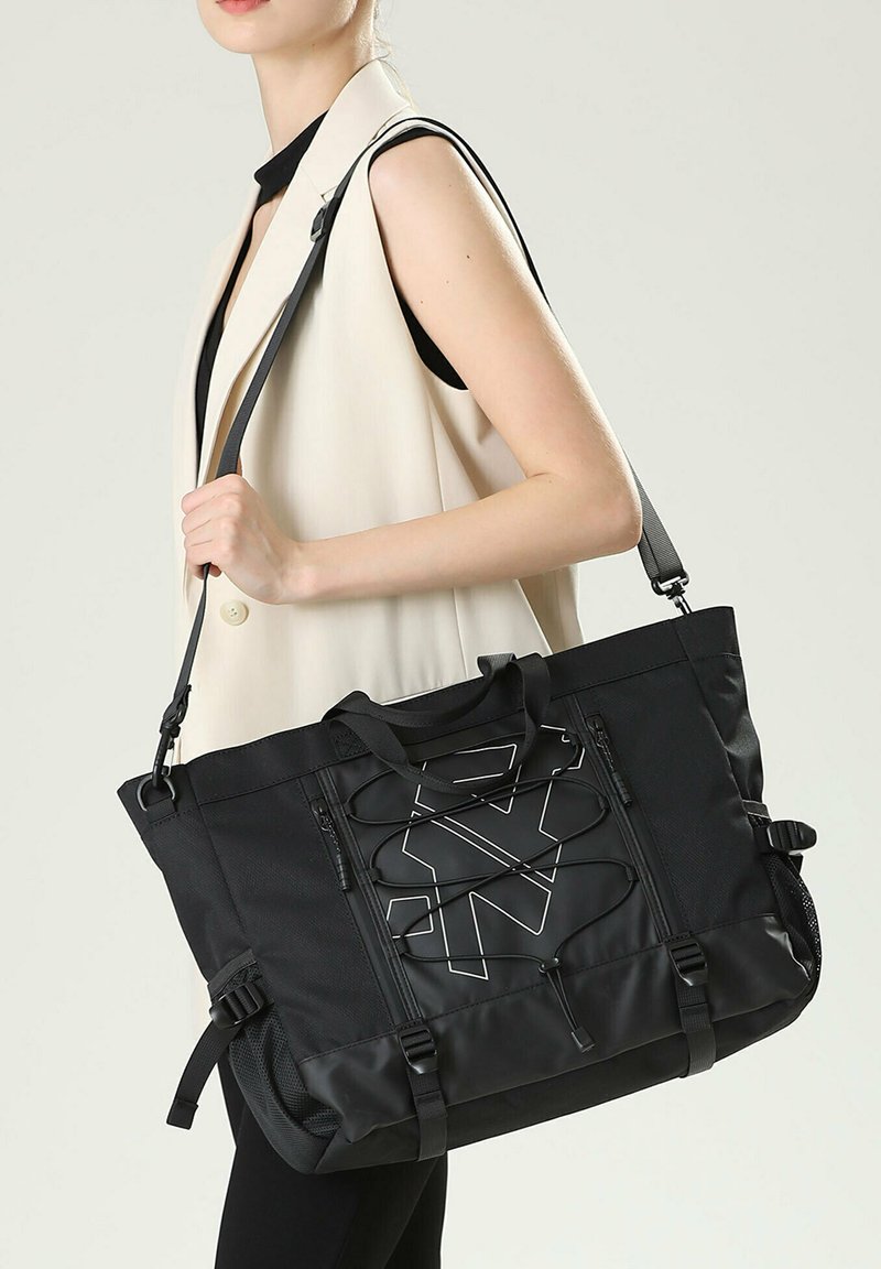 Borsa tote nera realizzata in nylon resistente, con un design geometrico caratterizzato da dettagli in corda, doppi manici, tracolla regolabile e tasche con zip.