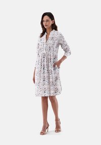 Abito con stampa floreale, colletto a camicia, plissettatura frontale, maniche lunghe e tasche laterali in un tessuto morbido e leggero.
