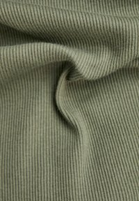 Ribbade tyger i dämpad grön färg, med en mjuk textur och subtila vertikala linjer, som visar draperingsdetaljer och veck.