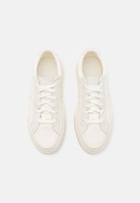 Sneaker bianche in tela con lacci, punta tonda, suola in gomma e cuciture tono su tono. Presenta un branding discreto sulla linguetta interna.