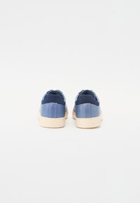 Blue sneakers with smooth leather and textile accents, featuring a cream rubber sole and rounded, padded heel. Rear view displayed.