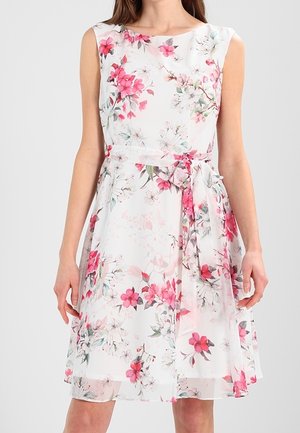 Robe blanche sans manches avec imprimé floral rose et rouge, munie d'un nœud noué à la taille et d'un ourlet au-dessus du genou.