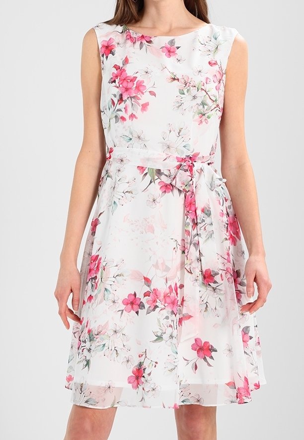 Robe blanche sans manches avec imprimé floral rose et rouge, munie d'un nœud noué à la taille et d'un ourlet au-dessus du genou.