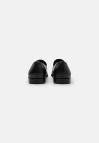 Black leather shoes with a sleek, minimalist design, rounded backs, and a smooth finish. Lightweight sole with subtle heel.