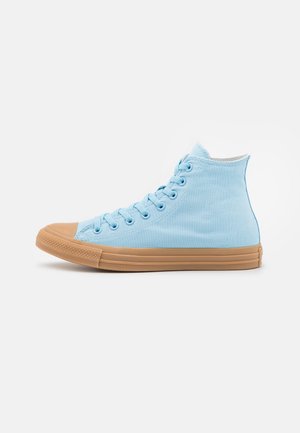 Hoher Sneaker aus hellblauem Stoff mit beiger Gummisohle und Zehenschutzkappe, von der Außenseite vor weißem Hintergrund gesehen.
