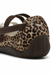 Leoparddruk flade sko med brune elastiske stropper. Blød, struktureret overdel med pelsagtig finish. Brun gummisål med et særpræget mønster. 