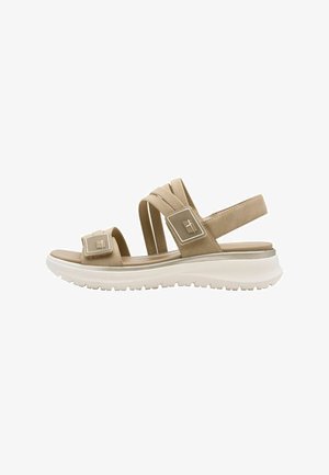 Beige sandaal met brede elastische bandjes, verstelbare metalen accenten en een witte, getextureerde zool voor grip. Casual, lichtgewicht ontwerp.