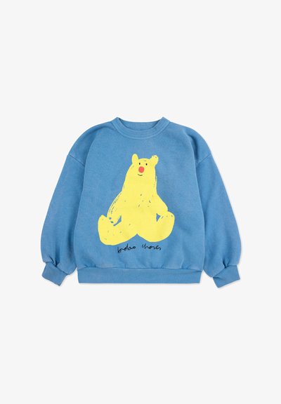 Sininen huppari, jossa on rento leikkaus, etupuolella suuri keltainen karhukuva ja ribbireunat hihoissa ja helmassa. Kuvan alla teksti lukee "bobo choses."