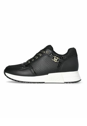 Sneaker nera con tomaia in pelle perforata, accenti testurizzati, lacci piatti e suola in gomma bianca con un leggero tacco. Logo del marchio visibile.