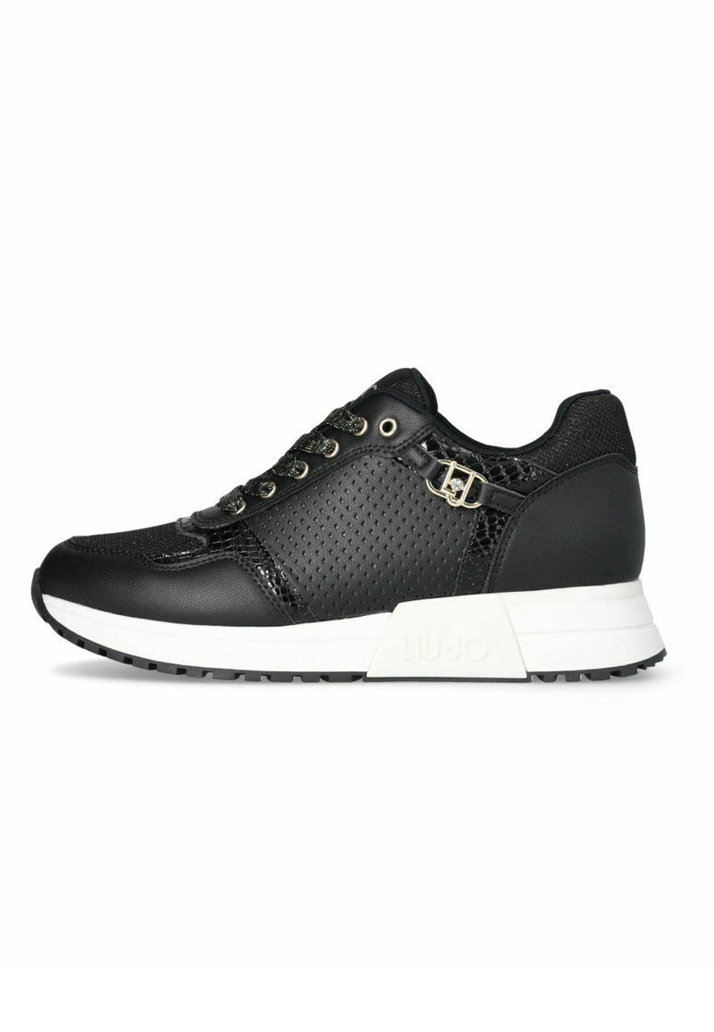 Sneaker nera con tomaia in pelle perforata, accenti testurizzati, lacci piatti e suola in gomma bianca con un leggero tacco. Logo del marchio visibile.