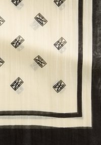 Sciarpa color crema con motivi geometrici neri. Tessuto leggero e trasparente con una texture tattile. Presenta bordi neri lungo i bordi.