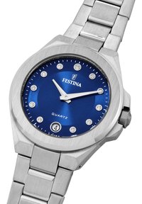 Silverfärgad klocka i rostfritt stål med en blå urtavla, som har applicerade timmarkörer, datumbeskrivning och två silvriga visare. Kvartsrörelse.