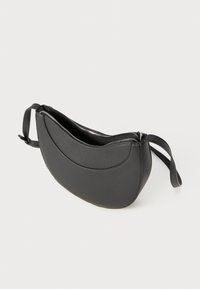 Black leather bag with a curved design, zip closure, and a narrow strap. Smooth texture with a minimalist aesthetic.