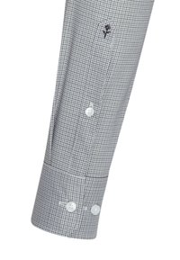 Manchet på langærmet skjorte med sort og hvidt småternet mønster, to hvide knapper og en lille broderet sort rose nær knapperne.