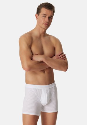 Witte geribbelde boxers met een zachte elastische tailleband, voorzien van een gevormde pouch voor ondersteuning. Het materiaal lijkt lichtgewicht en ademend te zijn.