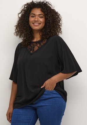 Top nero con scollo a V e dettagli in pizzo sul collo; maniche corte; tessuto leggero; abbinato a jeans in denim blu.