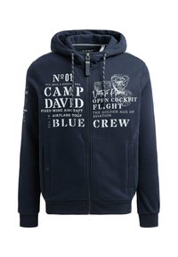 Sudadera con cremallera en azul marino, confeccionada en un tejido suave, con gráficos impresos en blanco con temática de aviación, bolsillos frontales y capucha con cordón.