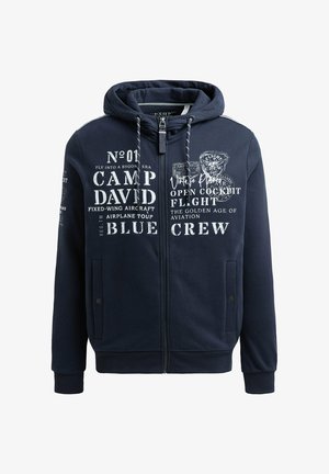 Sudadera con cremallera en azul marino, confeccionada en un tejido suave, con gráficos impresos en blanco con temática de aviación, bolsillos frontales y capucha con cordón.