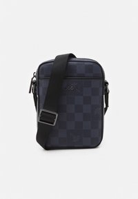 Bolsa preta compacta tipo tiracolo com padrão quadriculado, alça ajustável e bolso frontal com fecho de correr exibindo o logótipo da marca "JOOP!".