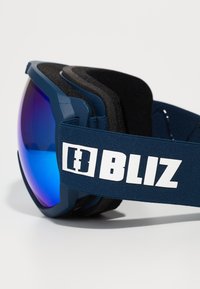 Óculos de esqui com lente espelhada azul, armação azul-marinho e almofadado preto. Faixa ajustável azul-marinho com o logótipo branco "BLIZ" para um ajuste seguro.