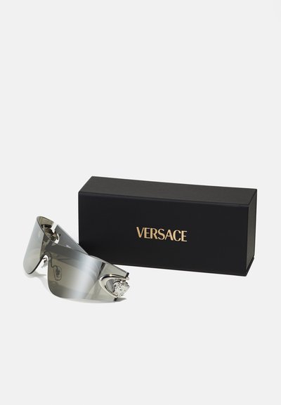 Versace-Sonnenbrillen mit grau getönten Gläsern, metallischen Rahmen und dekorativer silberner Hardware. Begleitet von einer schwarzen Box mit goldenem Logo.
