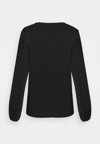 Černý top s dlouhými, texturovanými rukávy; hladká látka těla kontrastuje s vzorovaným, poloprůhledným materiálem rukávů a řasenými manžetami.