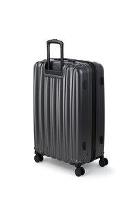 Walizka twarda w ciemnoszarym kolorze z pionowymi rowkami, wysuwaną rączką, czterema kółkami i zamkiem błyskawicznym zapewniającym łatwy transport.