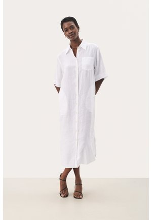 Abito camicia bianco in lino con frontale a bottoni, maniche corte, taschino sul petto e due tasche laterali. Design lungo fino al pavimento con vestibilità comoda.