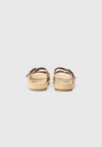 Sandales marron avec deux brides, une semelle intérieure texturée et une semelle tressée. Présente des accents métalliques et une finition lisse et mate.