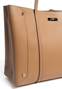 Sac fourre-tout en cuir beige avec une finition texturée, des accents de quincaillerie dorée et des détails de couture visibles. Présente une forme structurée et un marquage minimaliste.