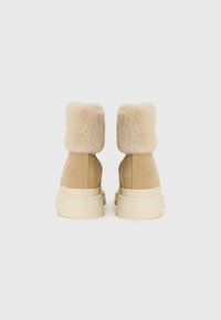Bottines en suède beige avec un col en fausse fourrure fluffy de couleur beige clair et des semelles épaisses de couleur crème. Design simple, sans motifs visibles.