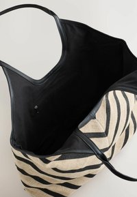 Große Tragetasche mit einem zebra-gestreiften Äußeren und schwarzen Lederakzenten, die eine Innentasche und einen offenen oberen Blick zeigt.