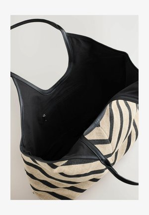 Velika torba s črtastim zebra vzorcem na zunanjosti in črnimi usnjenimi detajli, ki prikazuje notranji žep in odprt vrhnji del.