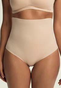 Beżowy bodysuit o wysokim stanie wykonany z miękkiego, elastycznego materiału; bezszwowa konstrukcja i gładka tekstura; odpowiedni do zakładania pod inne ubrania.