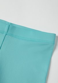 Turquoise stof met een gladde textuur, met een platte tailleband en een rechte rand. Stiksels zijn zichtbaar langs de bovenkant voor extra duurzaamheid.