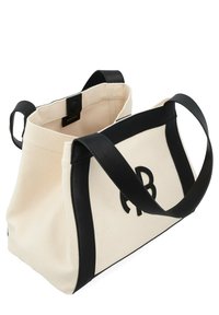 Sac en toile avec des accents et des poignées en cuir noir. Corps crème avec un logo noir bien en évidence. Ouvert sur le dessus, intérieur spacieux.