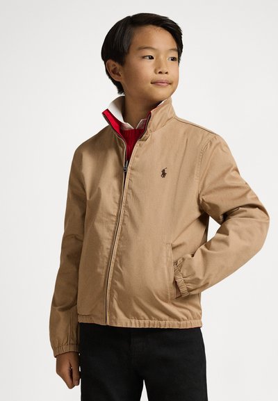 Könnyű anyagból készült khaki dzseki, magas gallérral, elöl cipzárral, oldalzsebekkel és egy kis logóval a mellrészen.