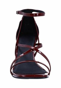 Burgundy strappy high-heel sandal with glossy finish, featuring crisscross straps and a single ankle strap, on a black sole.