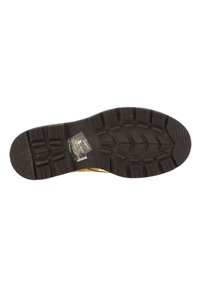 Semelle de chaussure en caoutchouc noir avec un motif de semelle texturé. Présente un revêtement synthétique et une étiquette rectangulaire au centre.