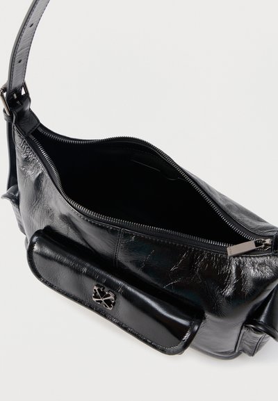 Μαύρη δερμάτινη τσάντα ώμου με ανοιχτό φερμουάρ στο επάνω μέρος, με μπροστινή τσέπη που διαθέτει μεταλλικό λογότυπο, σε λευκό φόντο.