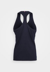 Námořnická modrá tílko s designem na závodní záda, vyrobené z hladké bavlněné látky. Obsahuje jemný červený akcent na zadním výstřihu.