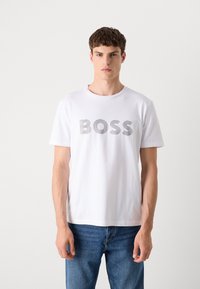 Witte katoenen T-shirt met korte mouwen, voorzien van een grijs gestreepte 'BOSS' logoprint op de borst. Ronde hals, ontspannen pasvorm.